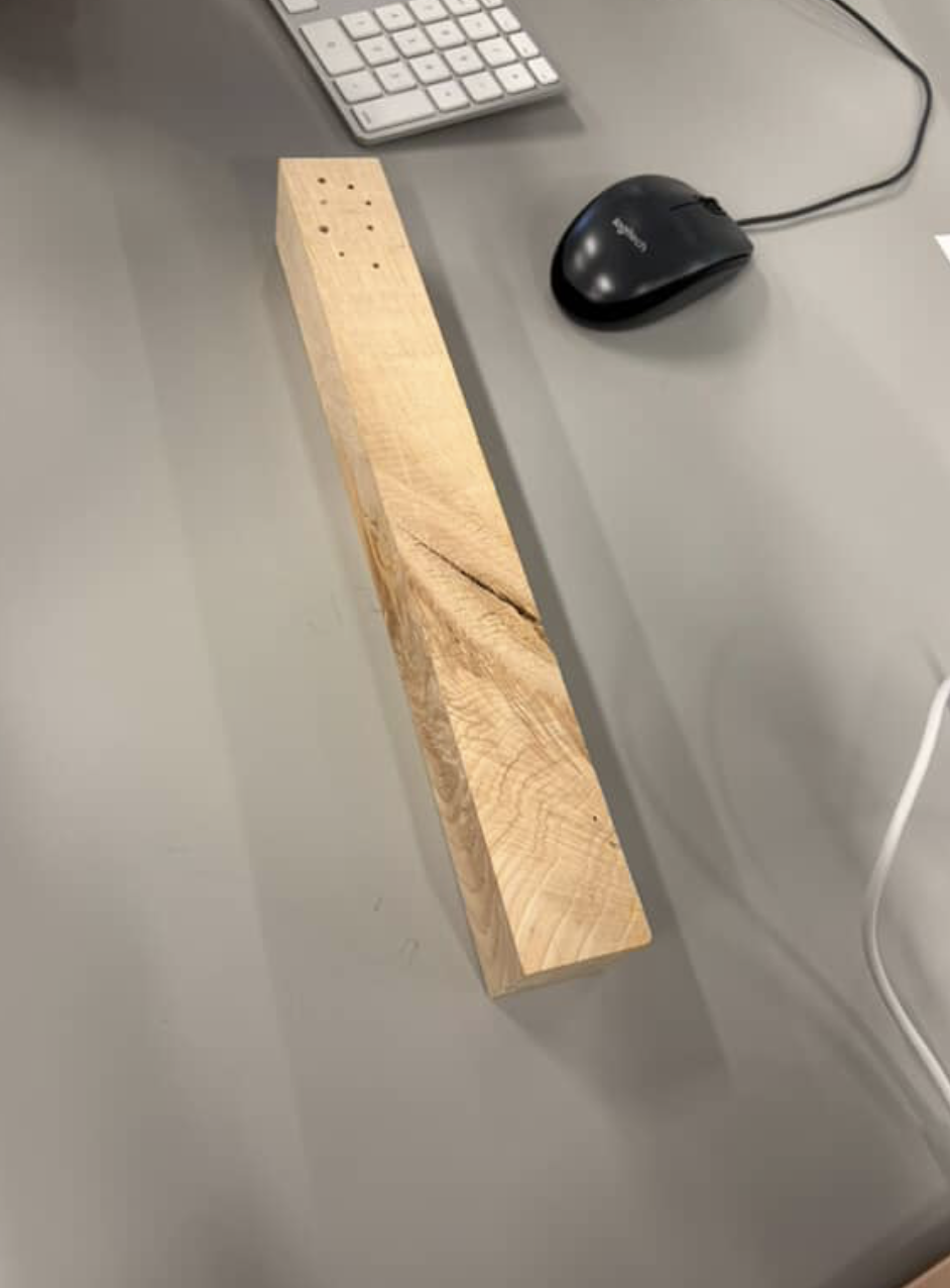 Wooden block <br> Material: solid unfinished wood. <br> Material state: rigid, dense piece of wood cut into a rectangular shape. <br> Material plasticity: Low plasticity, likely brittle and would splinter under force. can be shaped using tools (drilling, cutting, sanding) <br> Material use: Model making, carving, contruction, etc. 